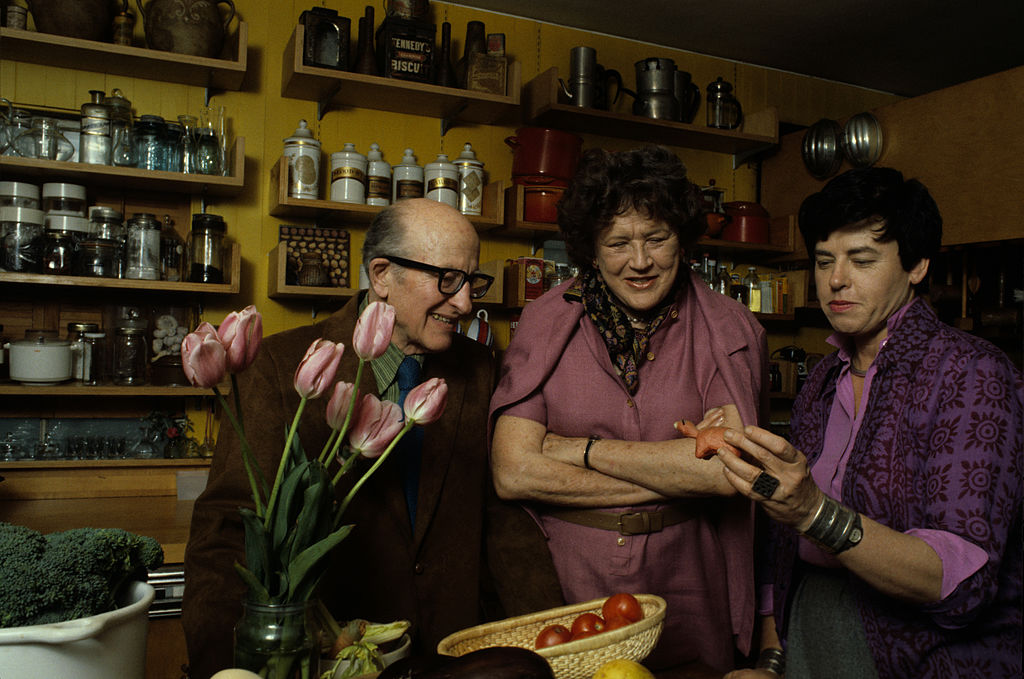 American chef, author, and television personality Julia Child (nee McWilliams, 1912 - 2004) (center) and her husband, Paul Cushing Child (1902 - 1994) look at a small sculptutr held by an unidentified woman in a kitchen, May 1978.