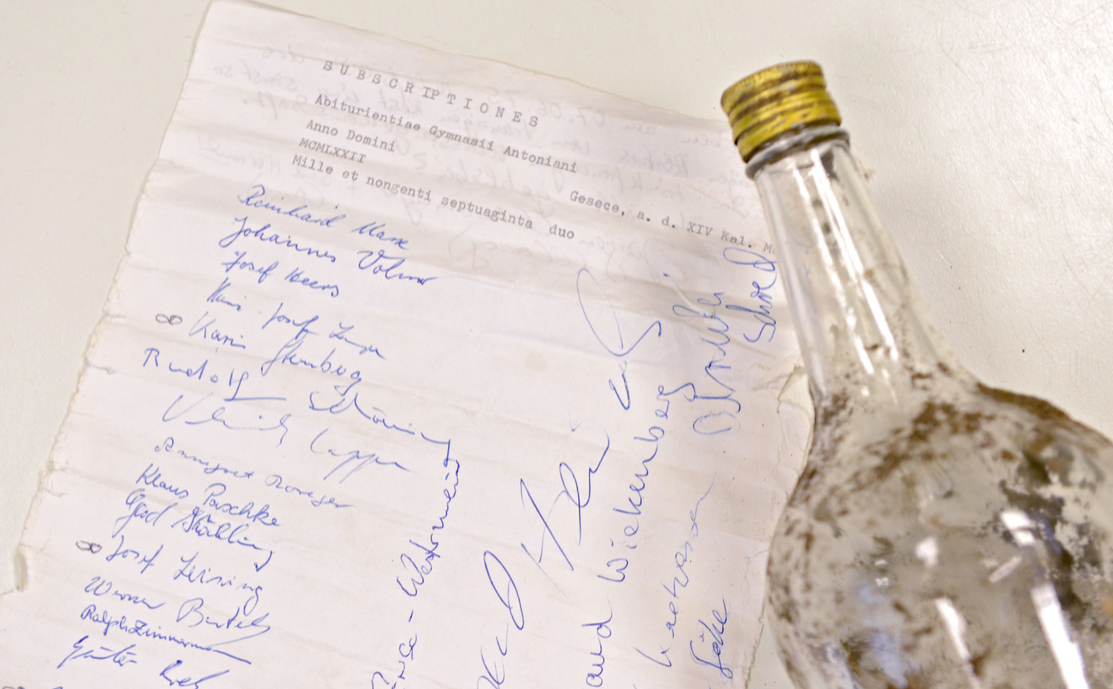 An old and dirty bottle with its contained message are presented on a table in Geseke, Germany