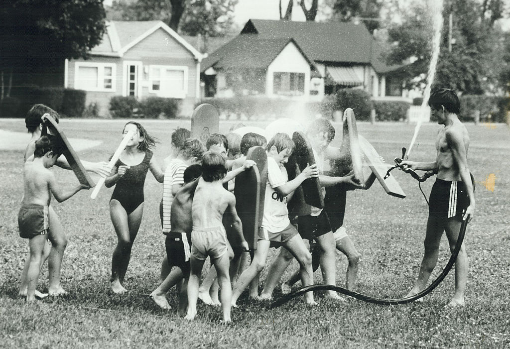 kids play with a water hose at summer camp