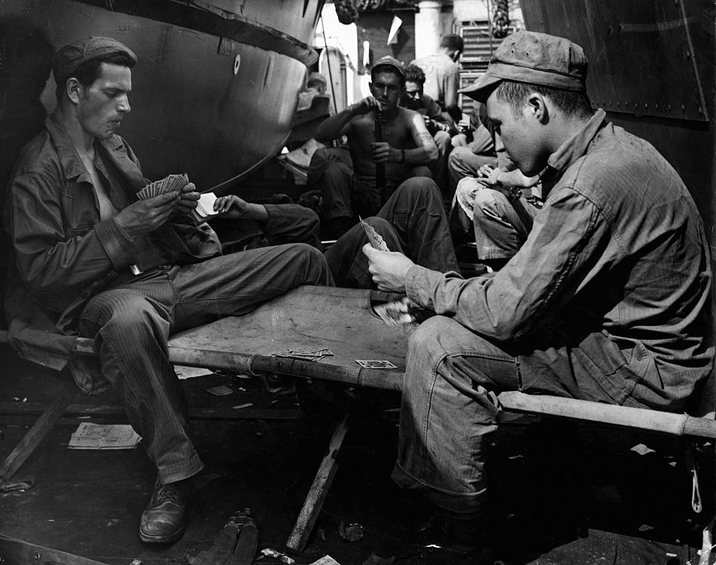 Marines play cards and clean their rifles on a ship bound for Iwo Jima