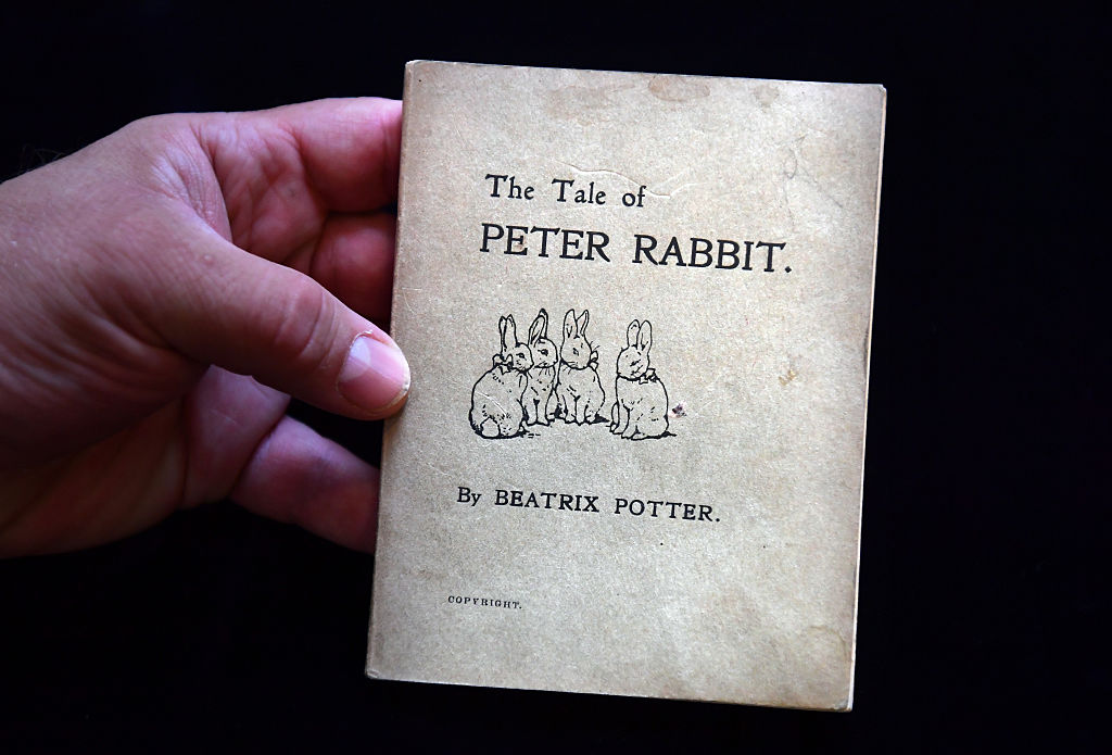 close up of a hand holding the tale of peter rabbit first edition