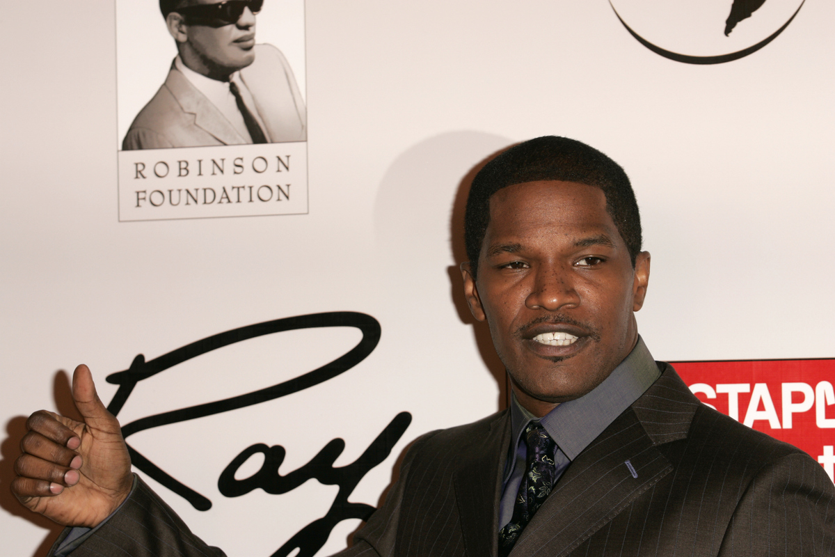 Jamie Foxx in front of a photo of Ray Charles