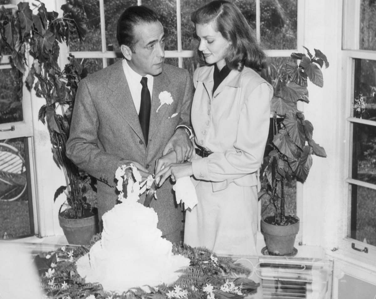 American actors Lauren Bacall and Humphrey Bogart cut the cake at their wedding.