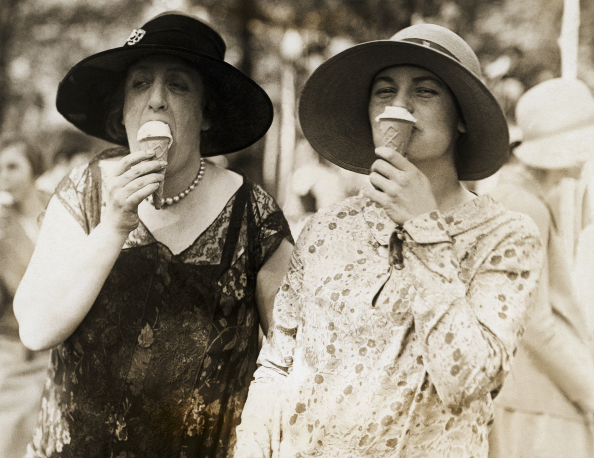 Madame Charalambos Simopoulos, wife the Minister of Greece to the United States, left, and Miss Suzette Dewey, daughter of the assistant secretary of the treasury, right, were caught in this informal pose while eating uce cream at the annual charity fete at the National Capital.