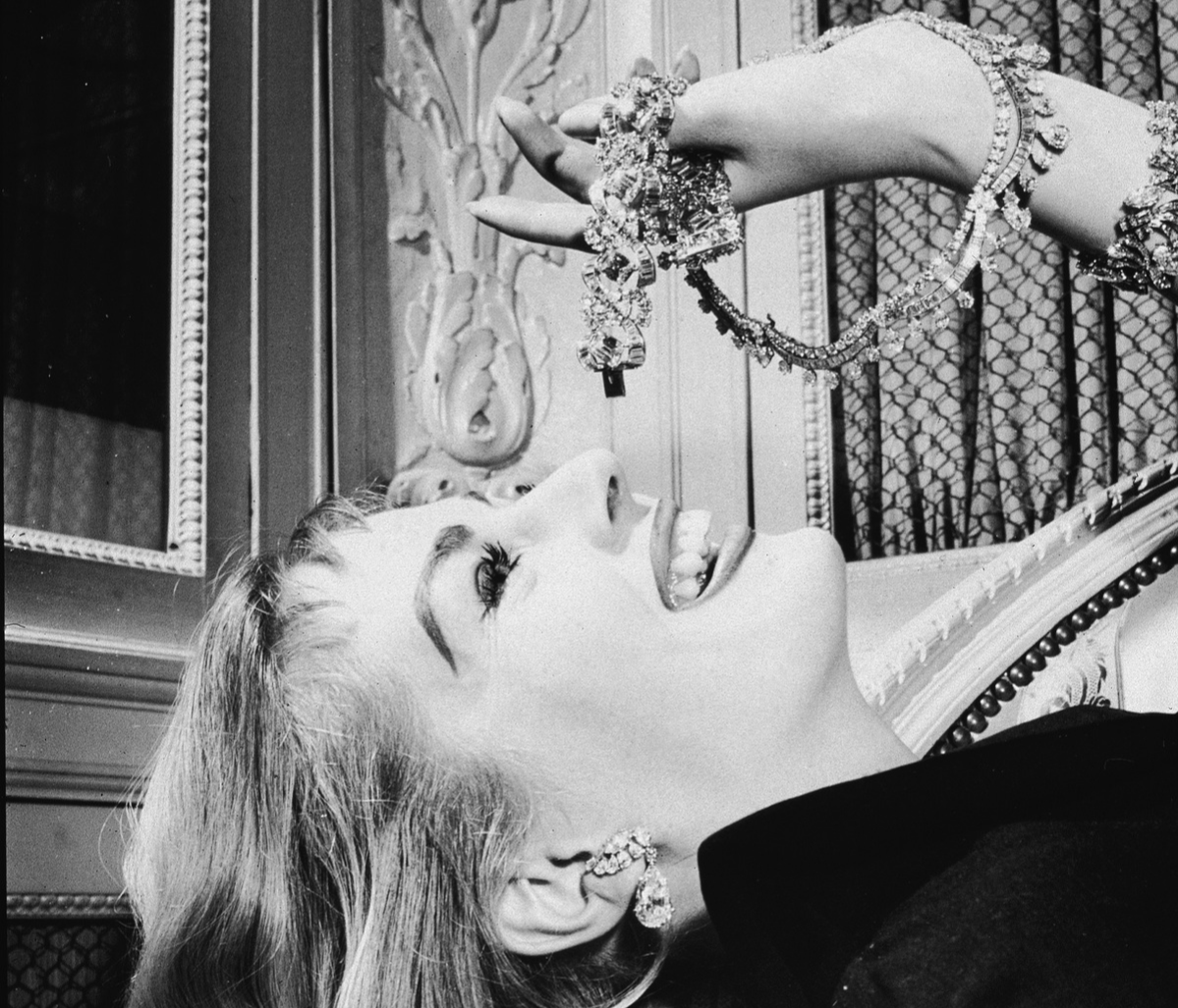Swedish-born actress Anita Ekberg mimics the pose of eating grapes with pieces of diamond Cartier jewelry