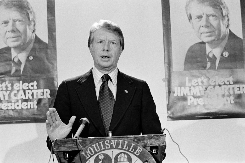 Louisville, Kentucky, USA - November 23, 1975: Then Governor of Georgia, Jimmy Carter stands in front of posters saying 'Let's Elect JIMMY CARTER President' and addresses the National Democratic Issues Convention.