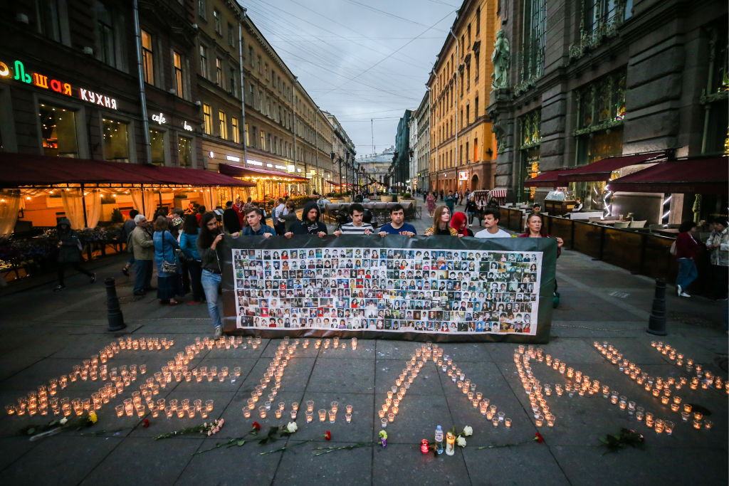 Russians hold up a sign with photographs of victims of the 2004 massacre.