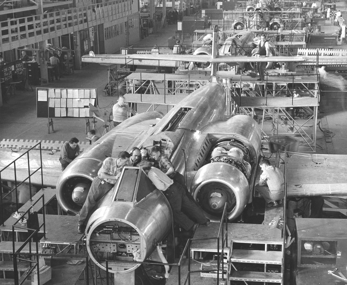 Men work on CF 100 jet fighter in an assembly line that fills the plant.