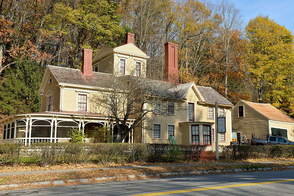 A large, yellow wood house is photographed, showing the house where the Alcott family lived at the end of their lives.