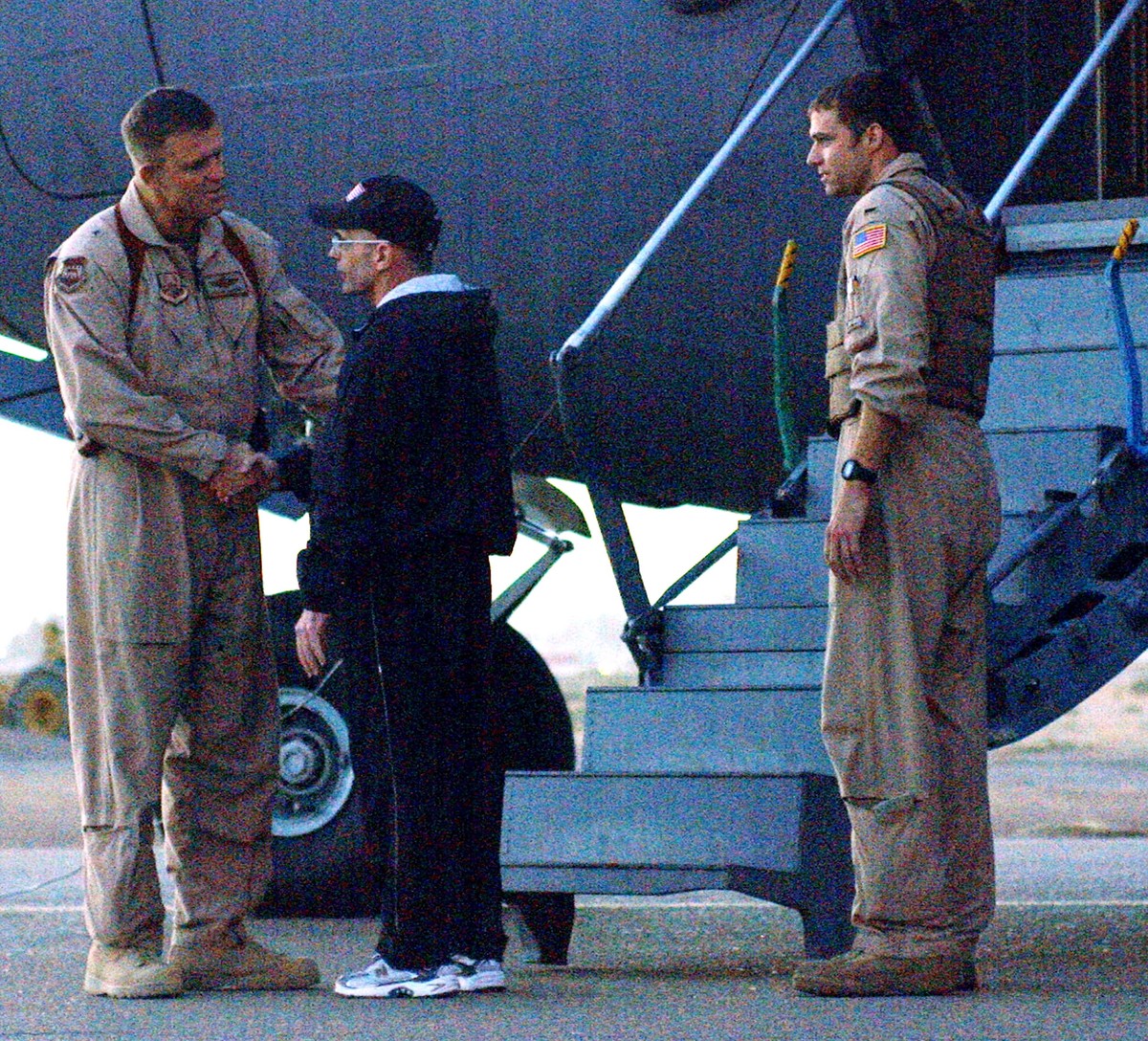 Roy Hallums shakes hands with a US troop in front of the plane that will take him home.