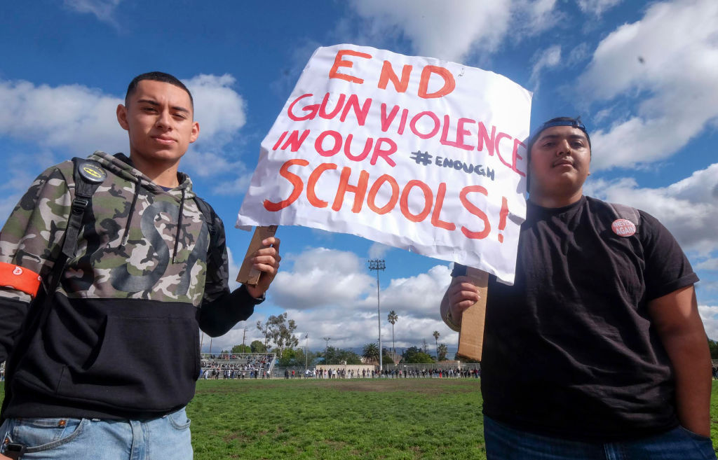 High schoolers hold up a sign to end gun violence in schools.