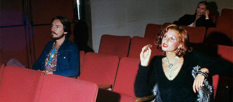 two women and a man sitting in a movie theater in the 1970s