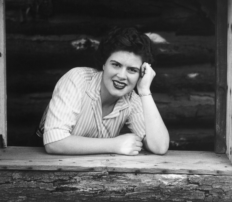 Patsy is photographed leaning on one elbow in a wooden window sill