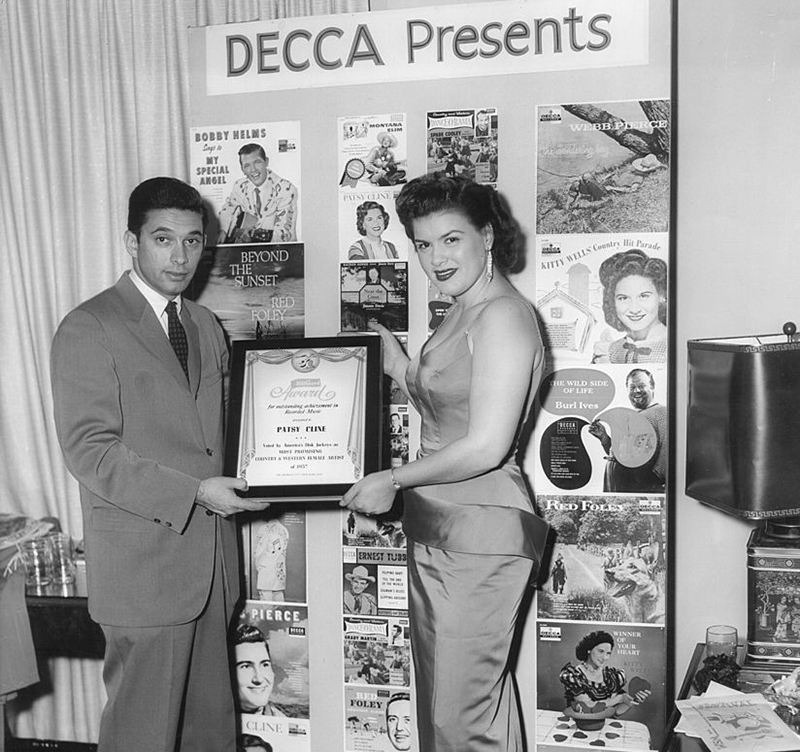 Patsy holds up a framed award from Decca