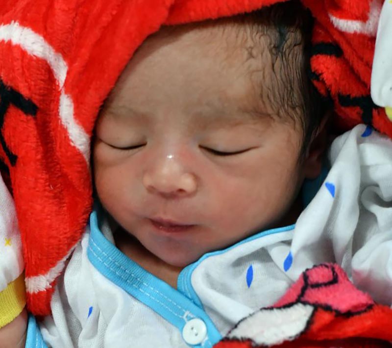 A baby sleeps surrounded by a soft blanket.