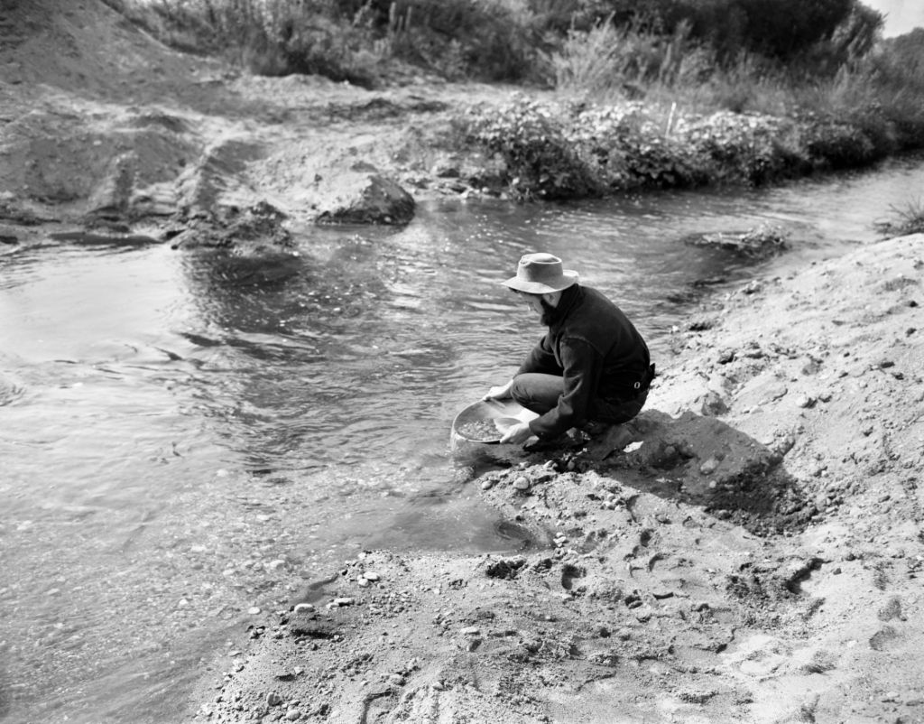 a person by a stream panning for gold