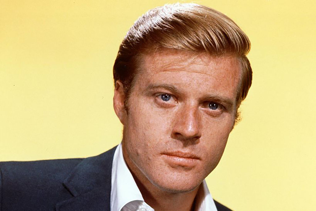 Redford posing in front of a yellow background