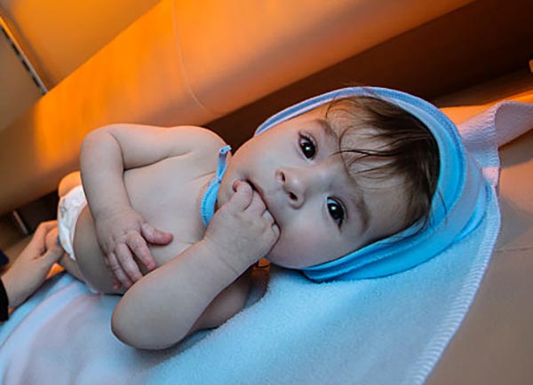 A baby on its back twists to the side to look at the camera.