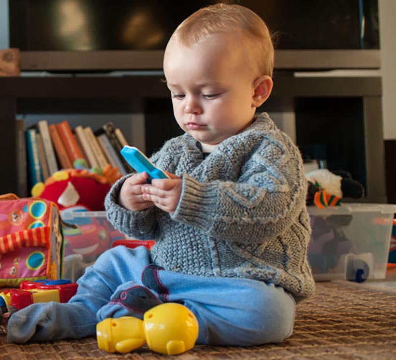 A baby plays with his toys on the living room floor.