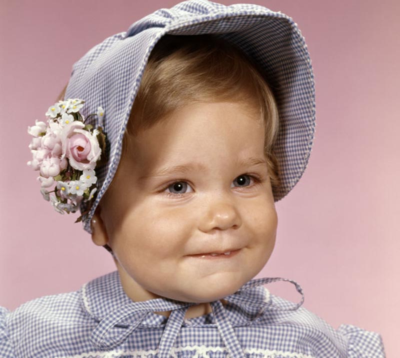 A baby girl grins to reveal the tips of two small teeth.
