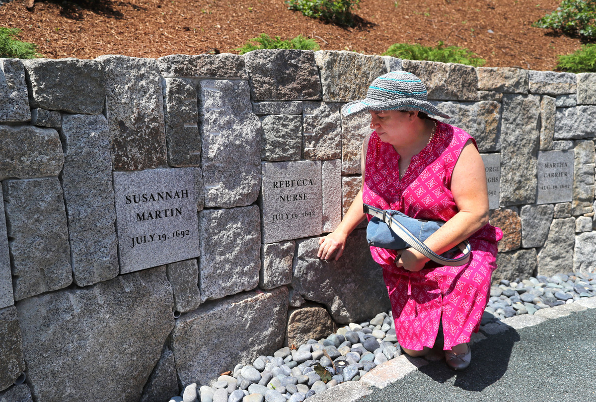 Benita Towle, the seventh great-granddaughter of Rebecca Nurse, stoops to touch the tombstone of Nurse