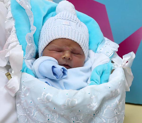 A sleeping baby is heavily bundled.