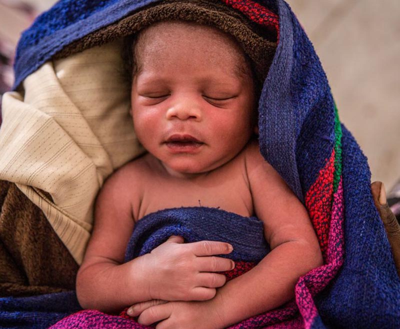 A baby sleeps in a pile of blankets.