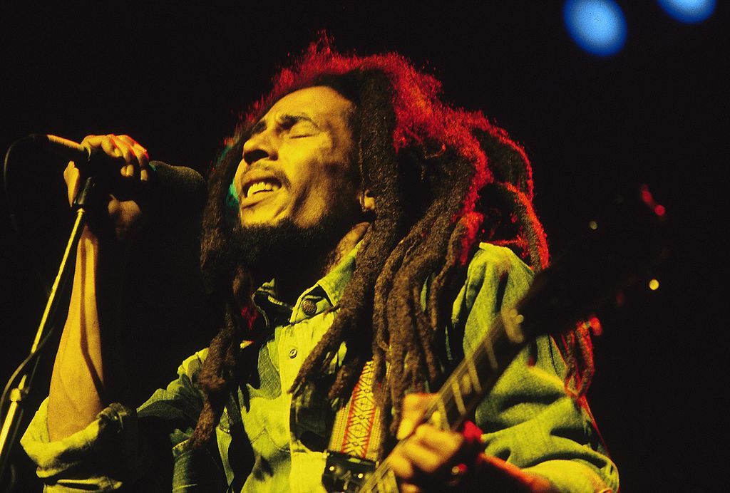 bob marley performing live on stage under red, yellow, and green lights