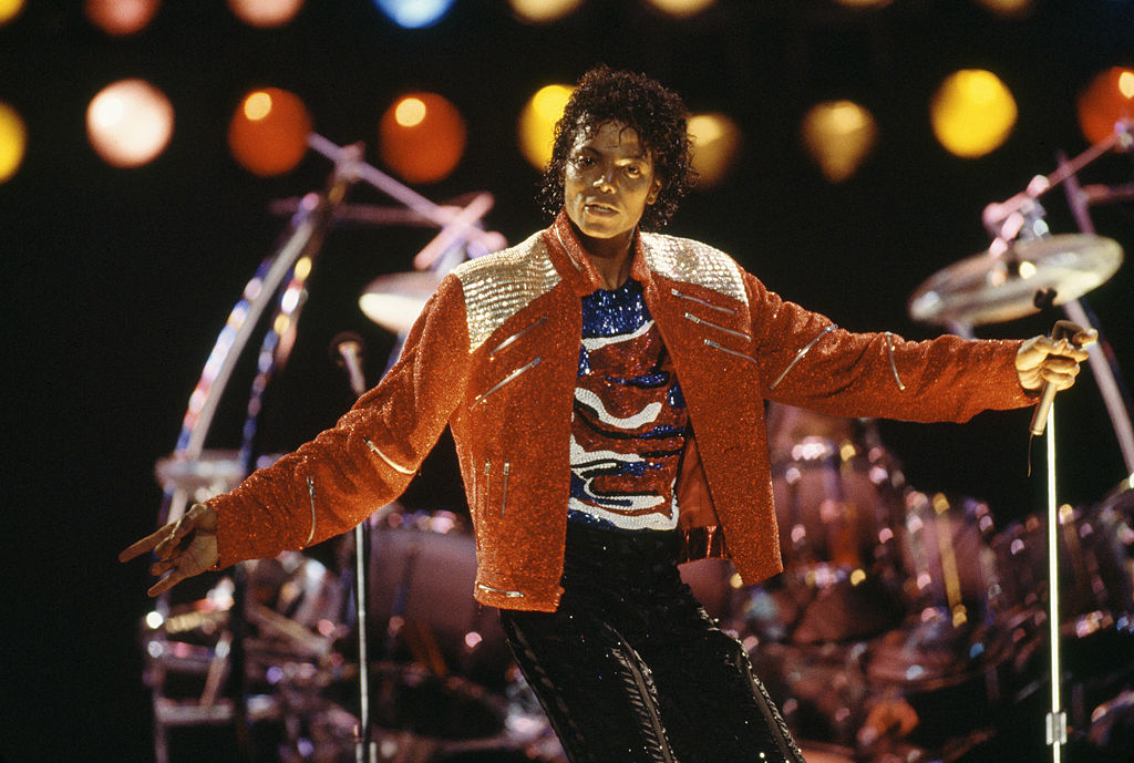 michael jackson performing on stage in a bedazzled red jacket in 1987