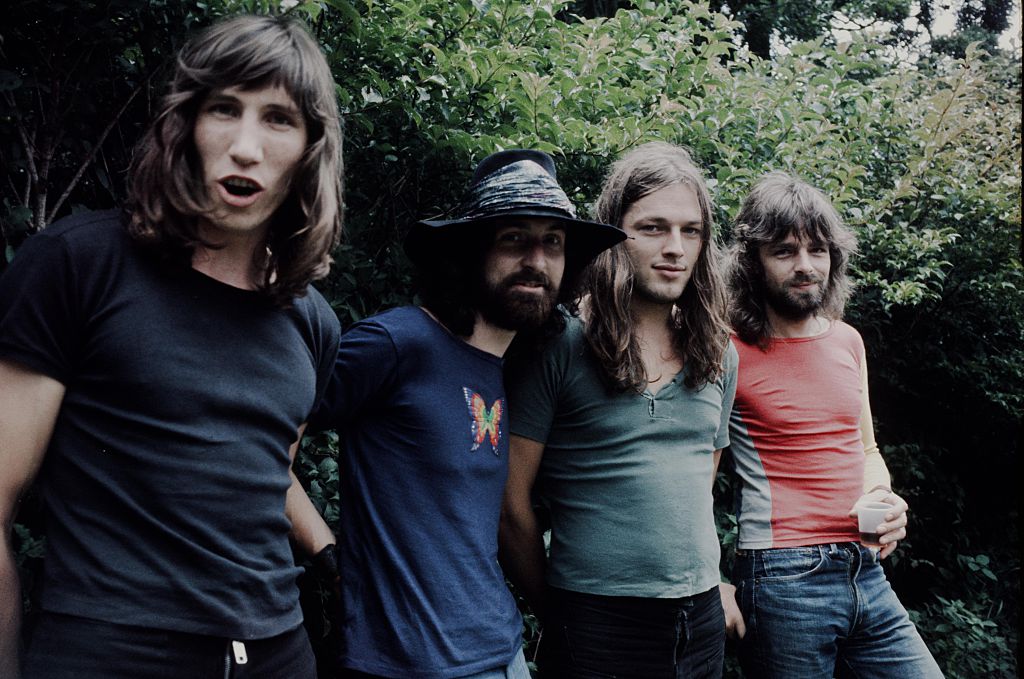 pink floyd band members in front of a plant outside