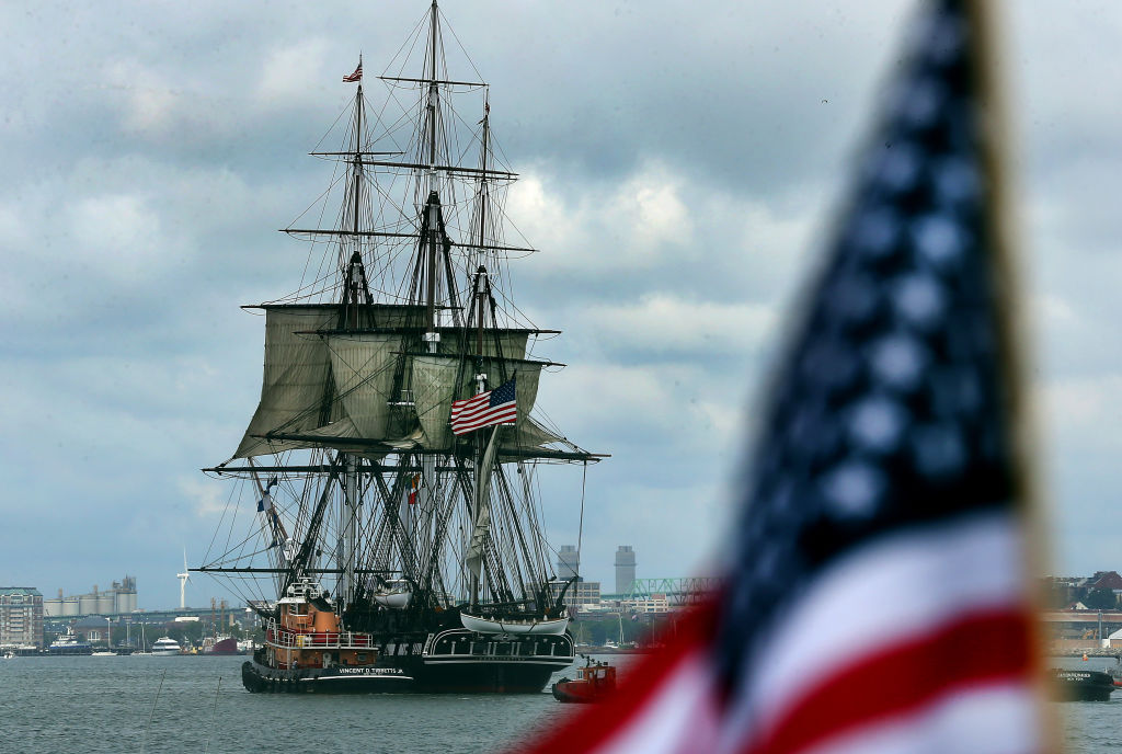 The USS Constitution sails in front of the American flag.