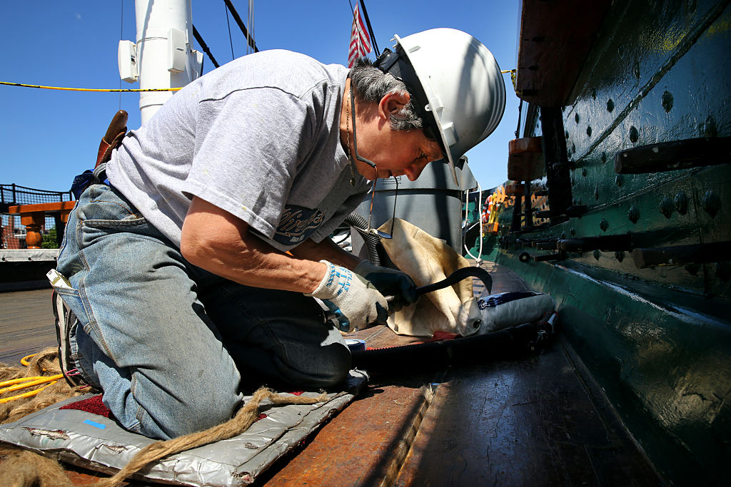 A worker performs repairs on the USS Constitutional.