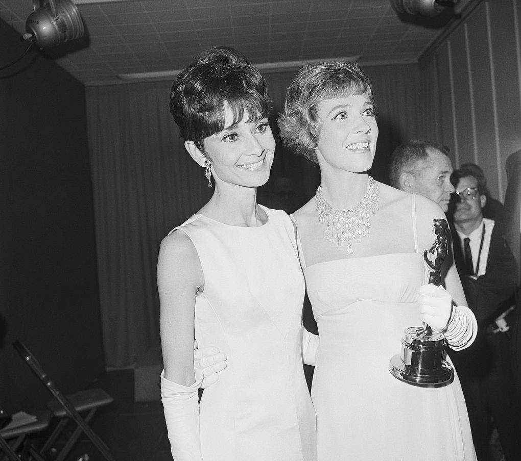 Andrews holds an Academy Award while posing next to Audrey Hepburn.