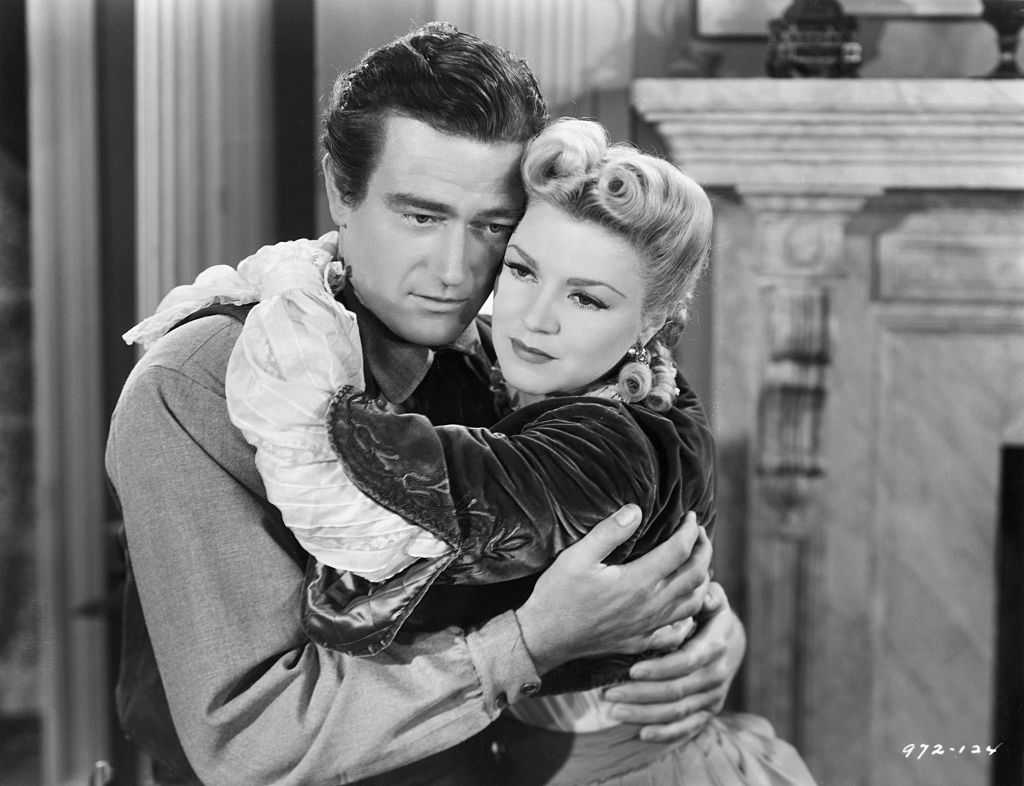 John Wayne and Claire Trevor embracing in Dark Command.