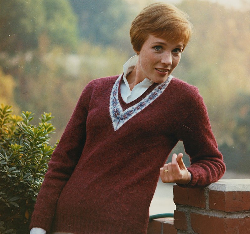 Julie Andrews poses against an open landscape.