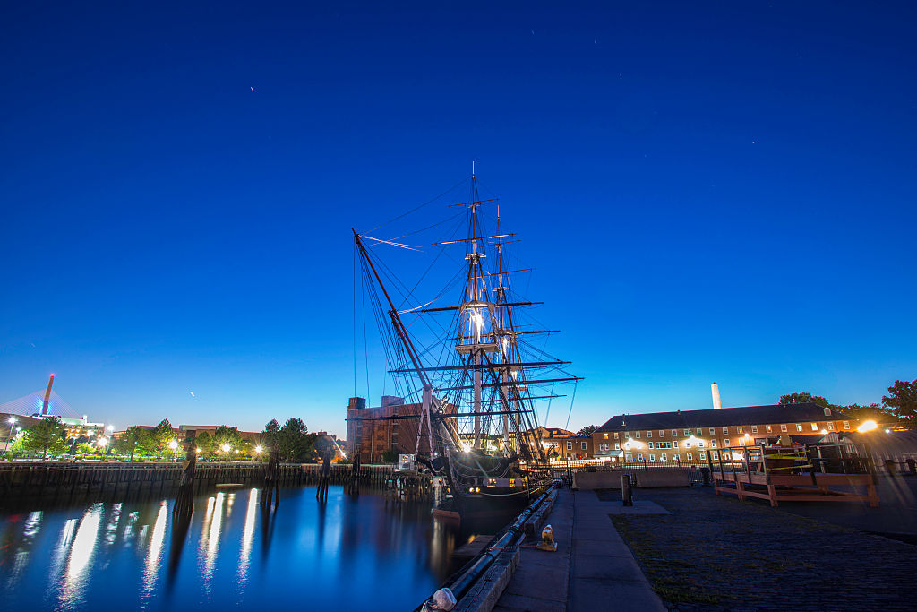 Surrounding lights illuminate the USS Constitution as it's docked at night.
