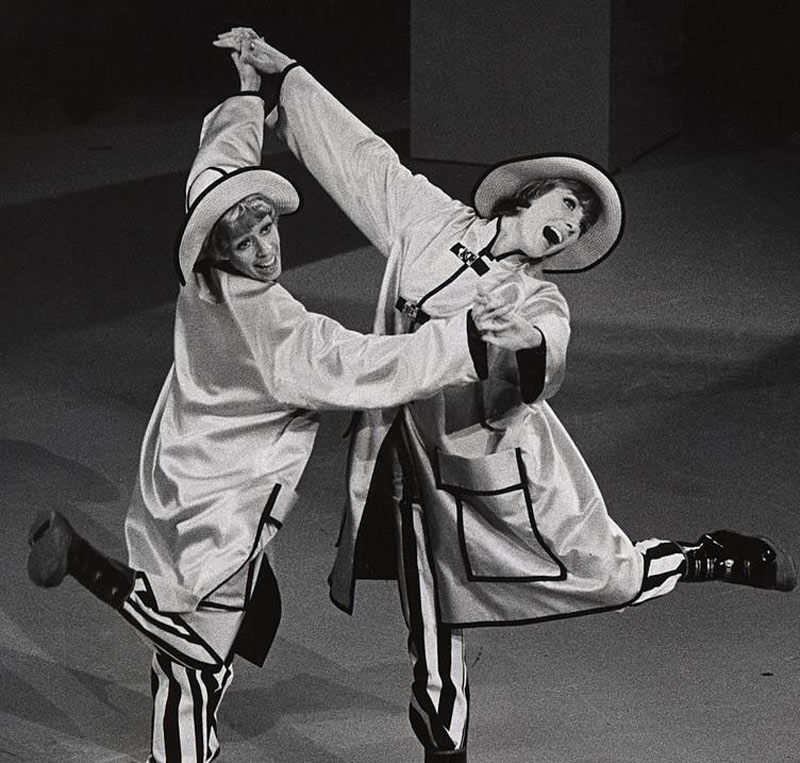 Julie Andrews joins hands with Carol Burnett while performing on a television special.