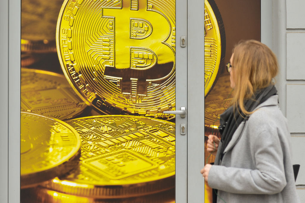 A lady passes in front of a Bitcoin exchange shop