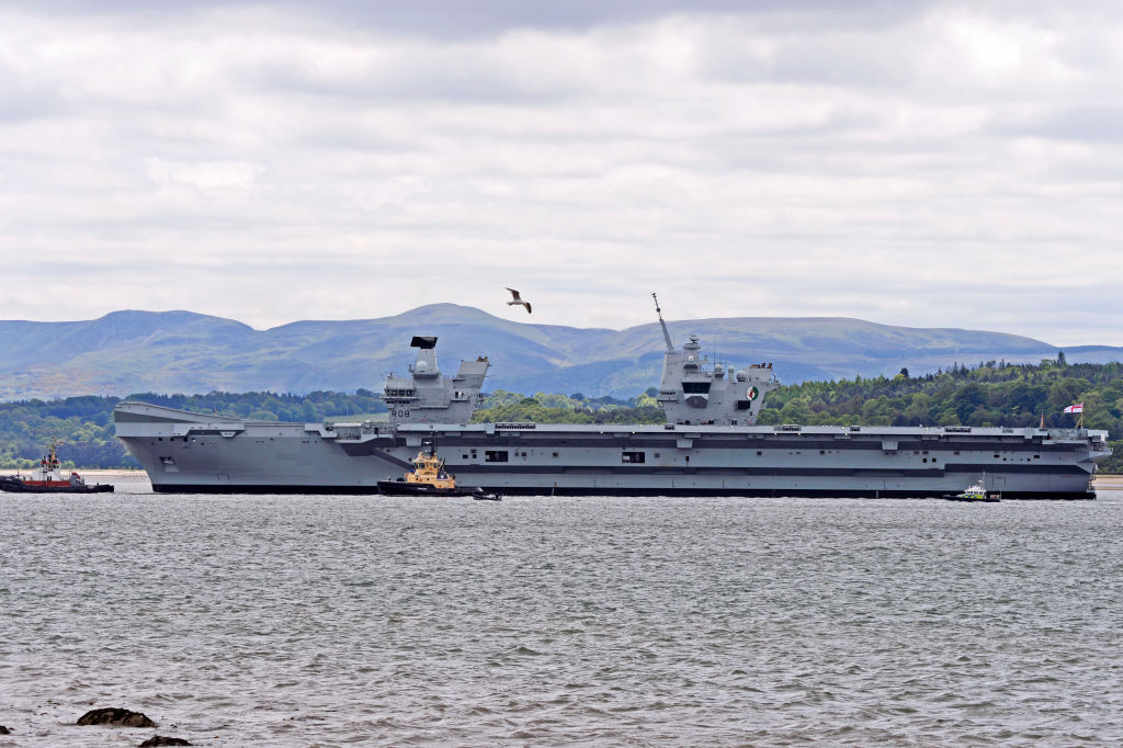 A bird flies over the HMS Queen Elizabeth as she sets sail.