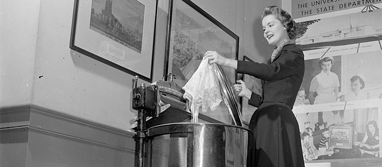 a woman in front of a copper washing machine