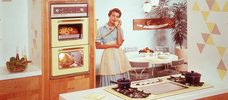 a woman talking on the phone while her food is cooking in the kitchen