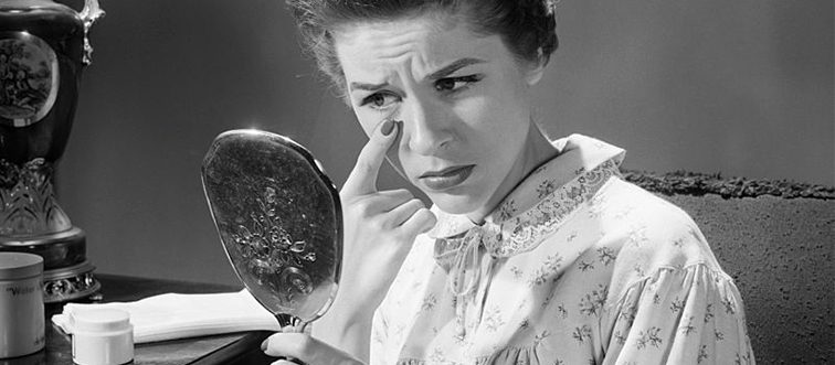 a woman looking at her face in the mirror