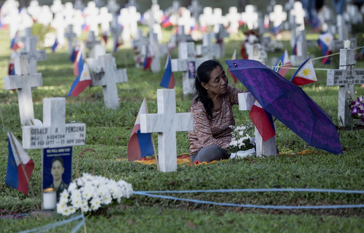 A Filipino relative visits the grave of a loved one in a cemetery.