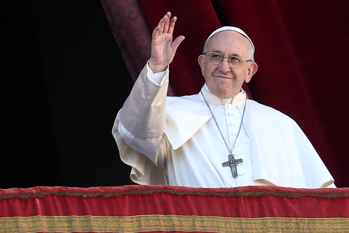 Pope Francis waves to the faithful from the central balcony of St Peter's Basilica.