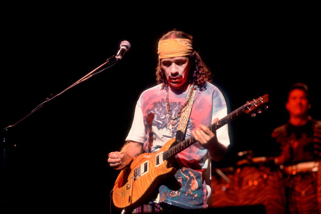 Carlos Santana plays guitar onstage.