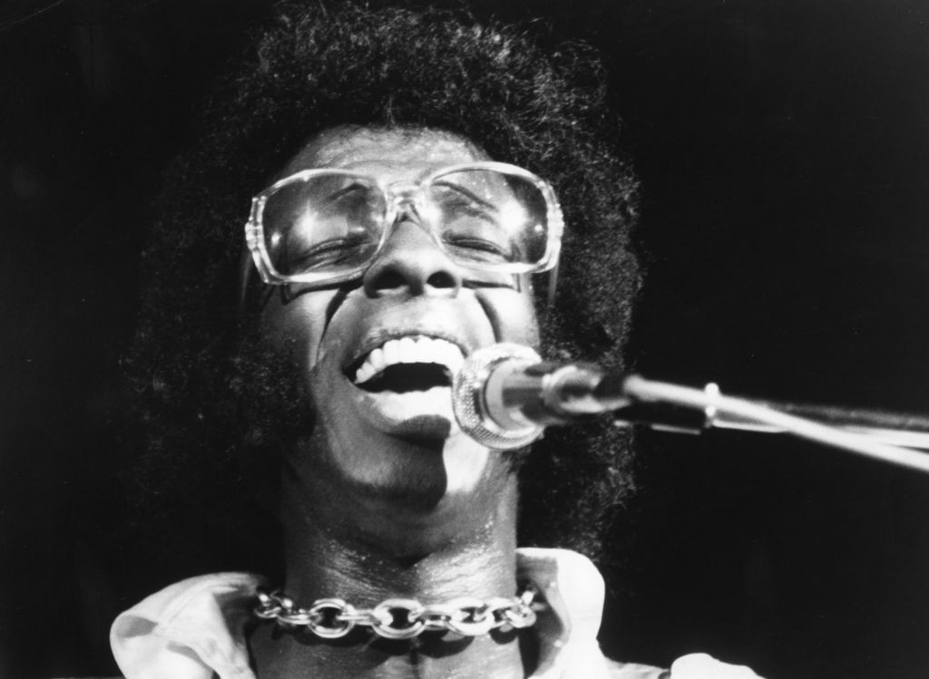 Sly Stone sings into a microphone.