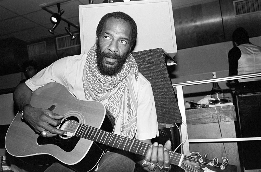 Richie Havens strums a guitar backstage.