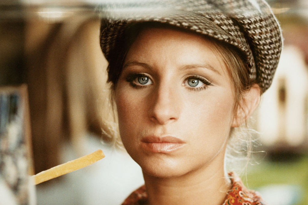 Barbra Streisand wears her hair tucked into a cap and a serious expression.