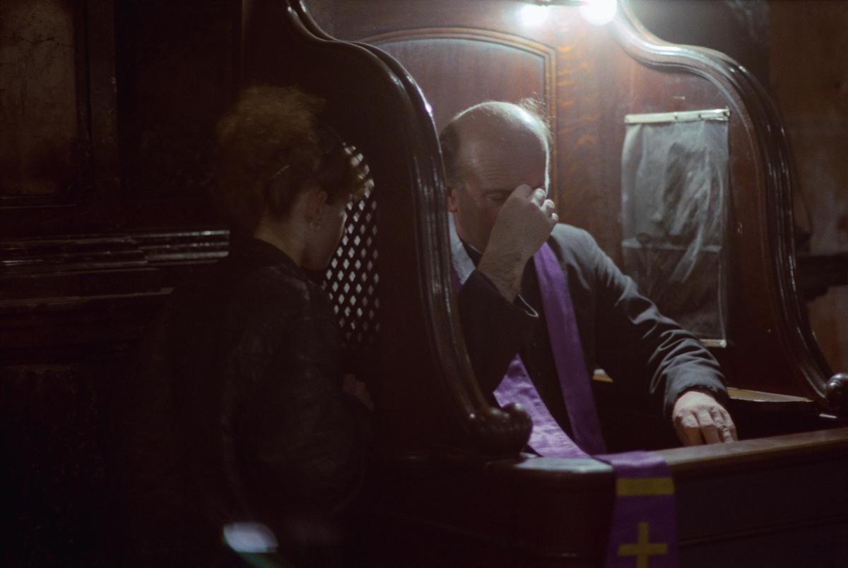 A woman gives confession to a priest.