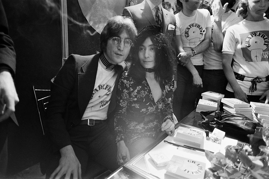 John Lennon and Yoko Ono sit in a crowd at a book signing.